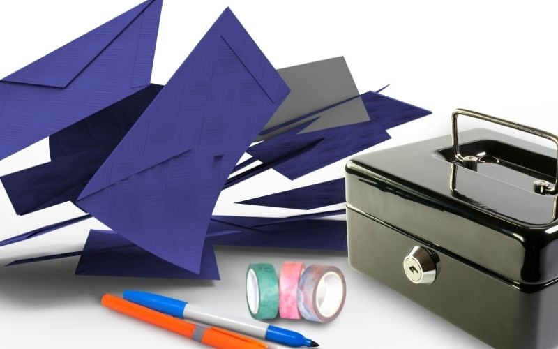 Photo of blue colored envelopes, two colored pens, three rolls of washi tapes and a black box with lock