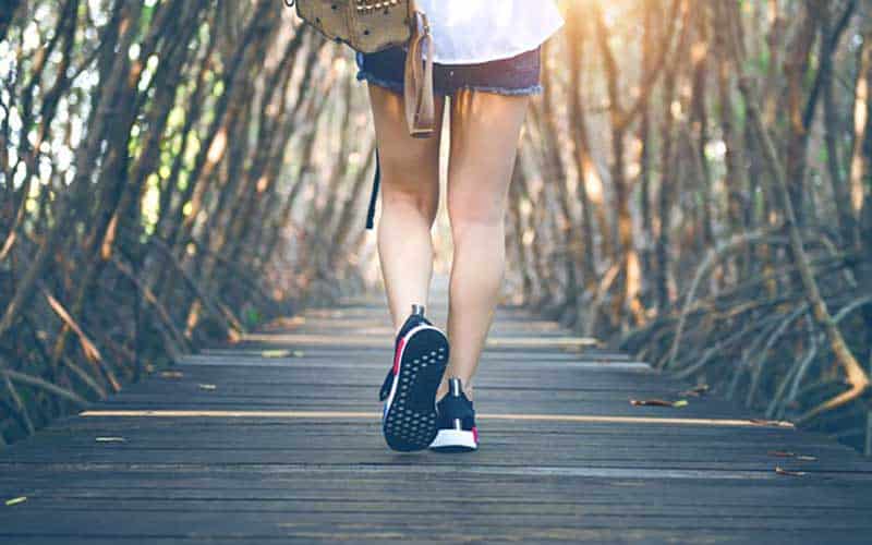 Picture of feet in running shoes, with female legs walking away from the camera.