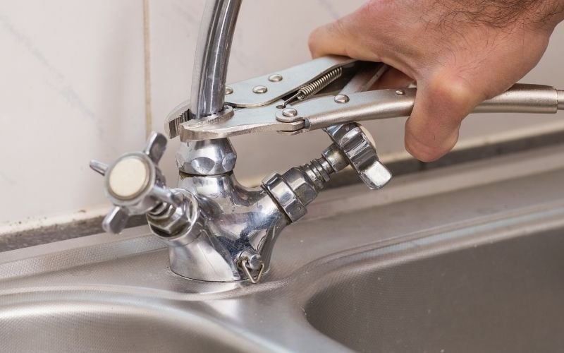 Photo of a hand holding a wrench attached to the faucet
