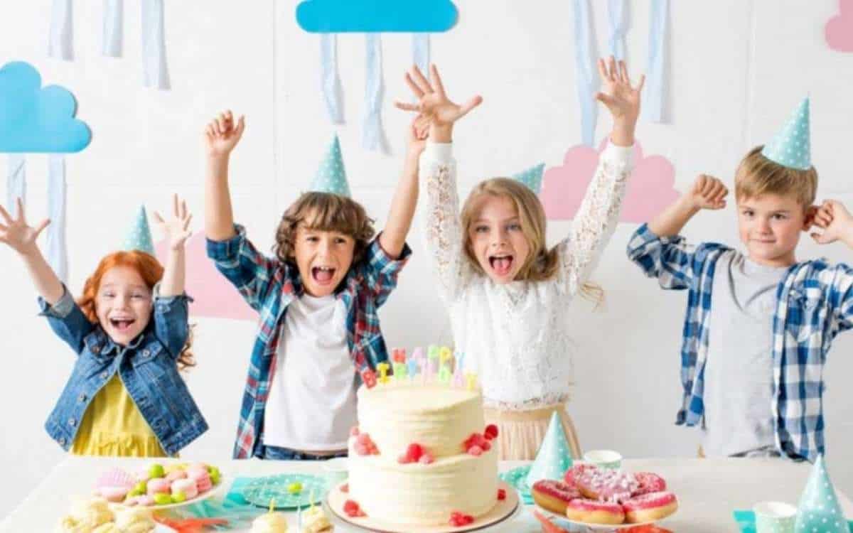 Photo of four happy children with with their hands raised in a kids party