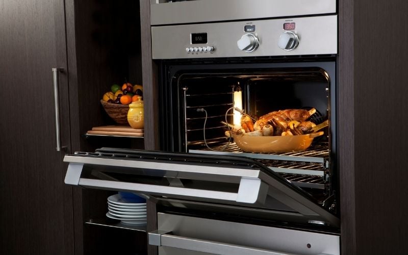 Photo of an open oven with baked chicken