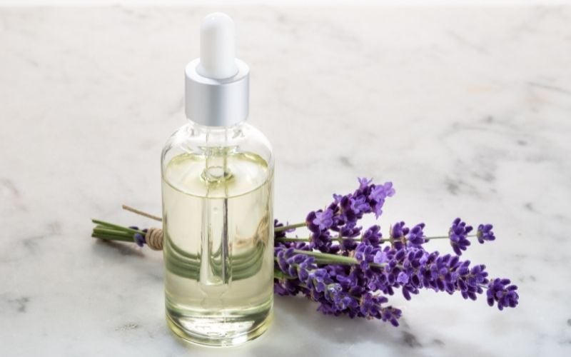 Photo of a small bottle with dropper filled with oil beside a lavender