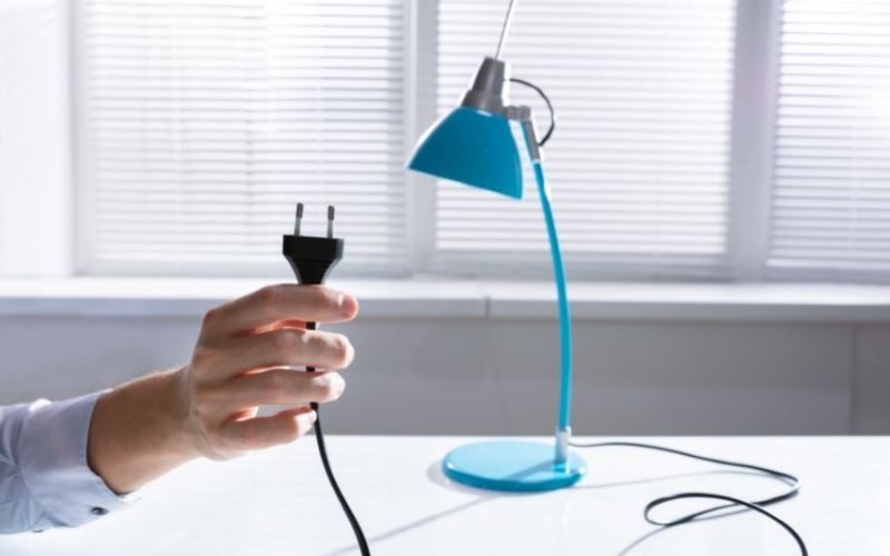 Photo of a hand holding a plug with blue lamp on a table