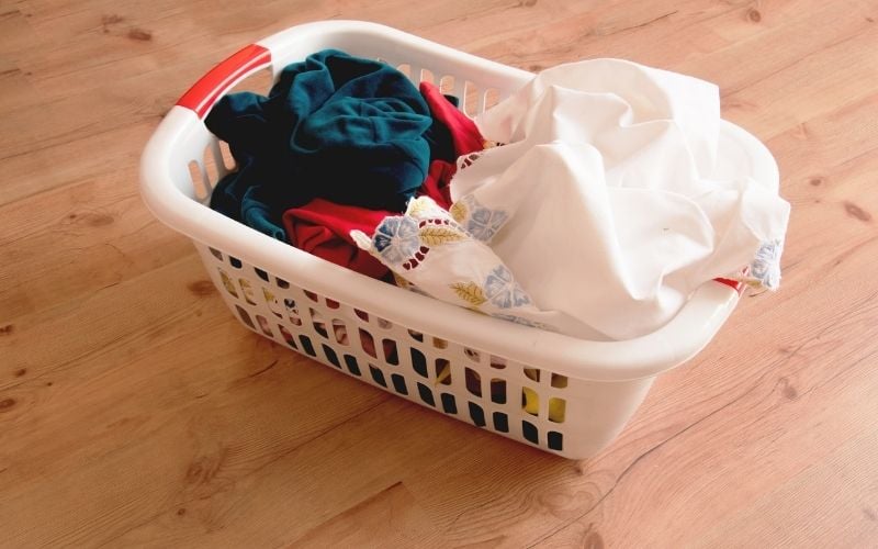 Photo of a laundry basket filled with clothes on the floor