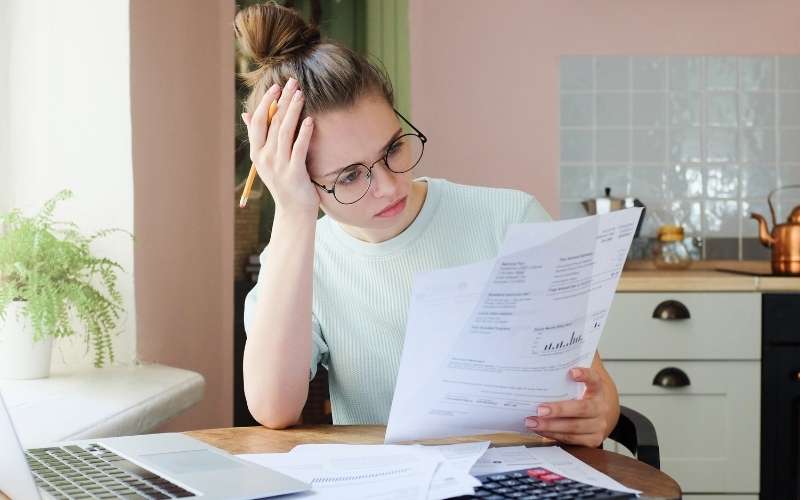 Woman with head in hands looking at bank statement in blog post about inspirational debt quotes